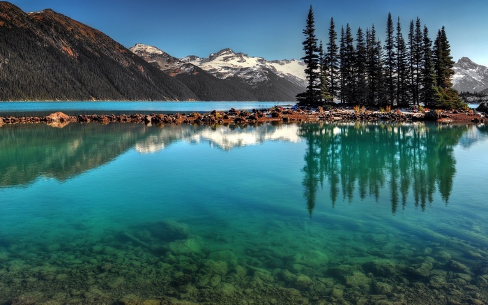 Turquoise lake with rocky island and snow-capped mountains