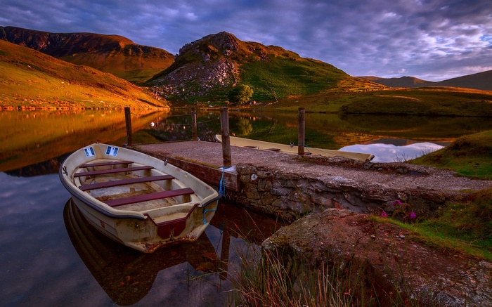 Boat docked on a lake with mountains at sunset