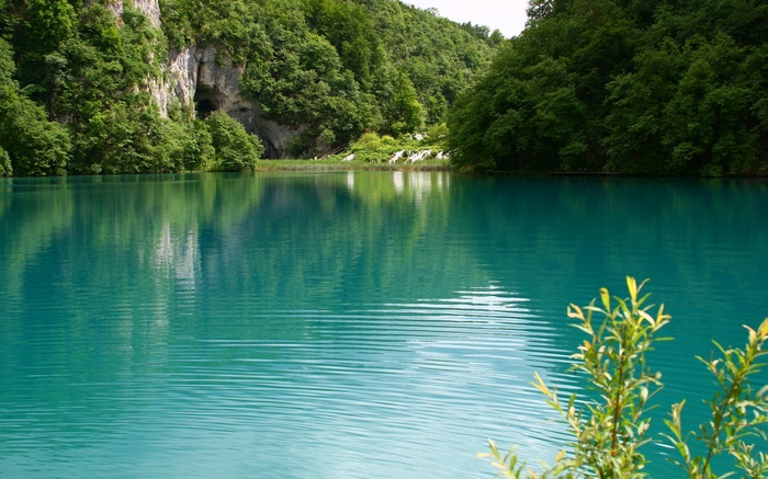 Turquoise lake with cave and forest