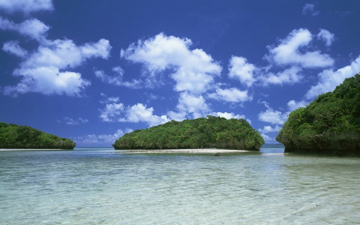 Islands in a clear blue ocean under a cloudy sky