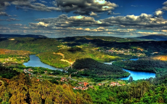 River valley with forests and villages under cloudy sky