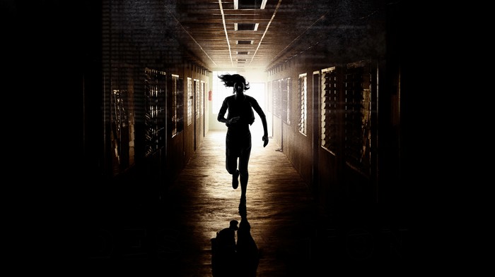 Silhouette of a person running down a dark hallway