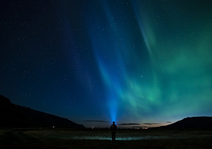 Man with flashlight watching Aurora Borealis