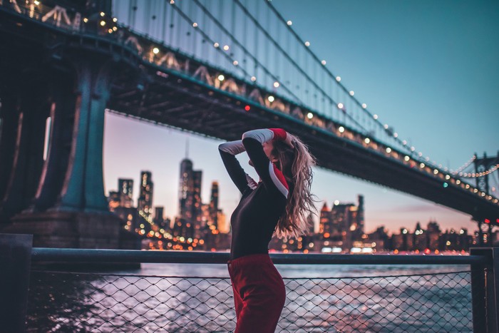 Woman posing near Brooklyn Bridge at dusk