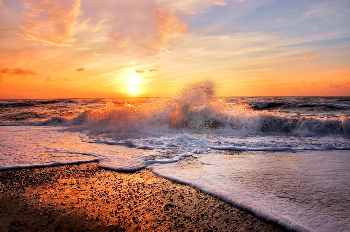 Ocean waves crashing on a beach at sunset