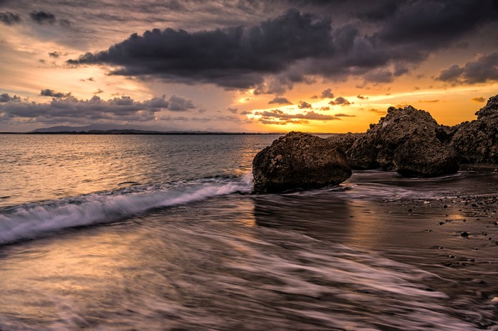 Sunset over the ocean with rocks and clouds