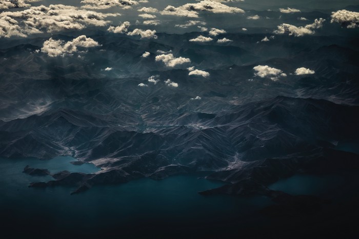 Aerial view of mountains and clouds over water