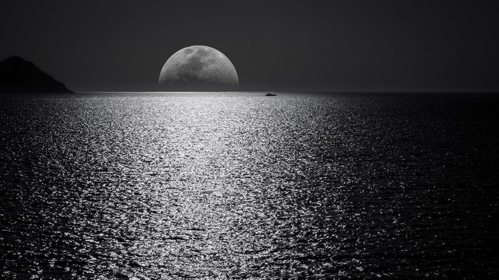 Moon over the ocean with a boat