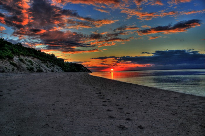 Sunset over a beach with a forested hill