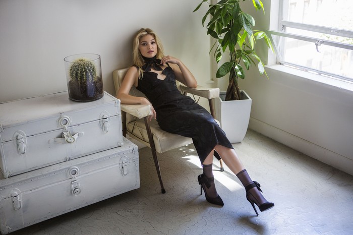 Olivia Holt in a black dress sitting in a chair
