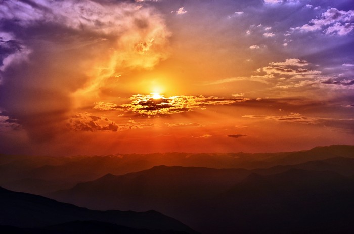 Sunset over mountain ranges with colorful clouds