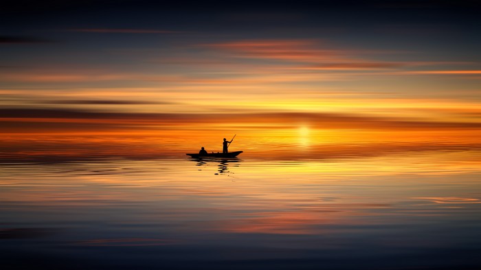 Two people in a boat at sunset over the ocean