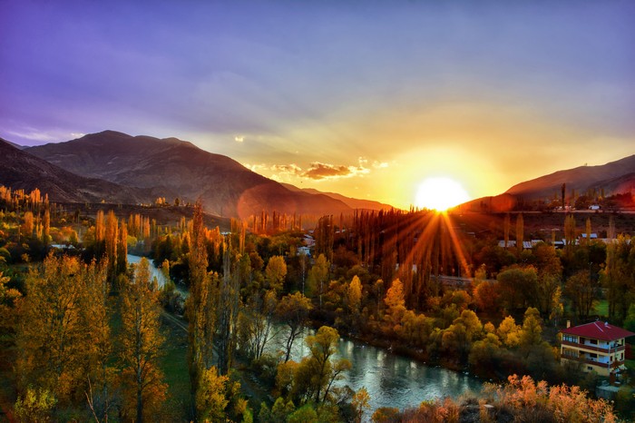 Sunset over mountains and a river valley with autumn trees