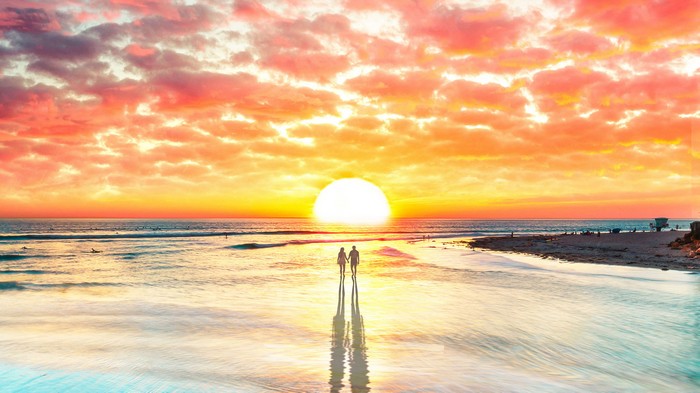 Couple walking on beach at sunset 4K