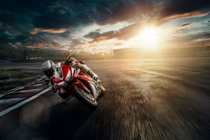 Honda motorcycle racing on a track at sunset