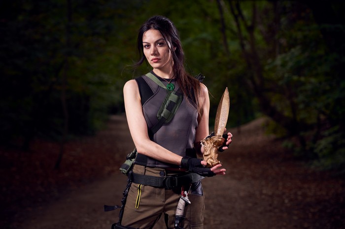 Lara Croft holding a golden knife in a forest