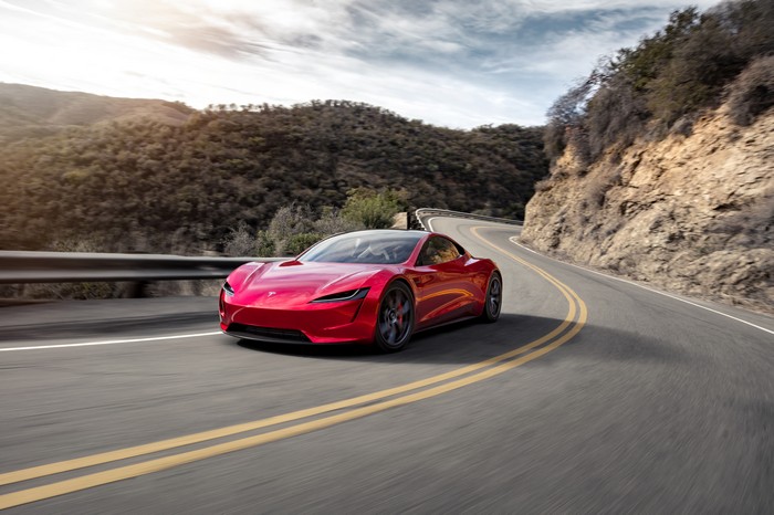 Red Tesla Roadster driving on a winding road