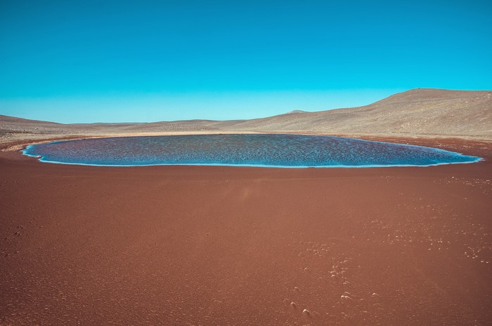 Red desert lake under a clear blue sky