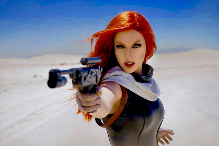 Woman with red hair holding a blaster in a desert