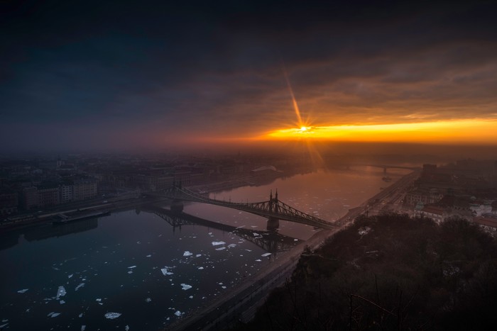 Sunrise over a city with a bridge and river