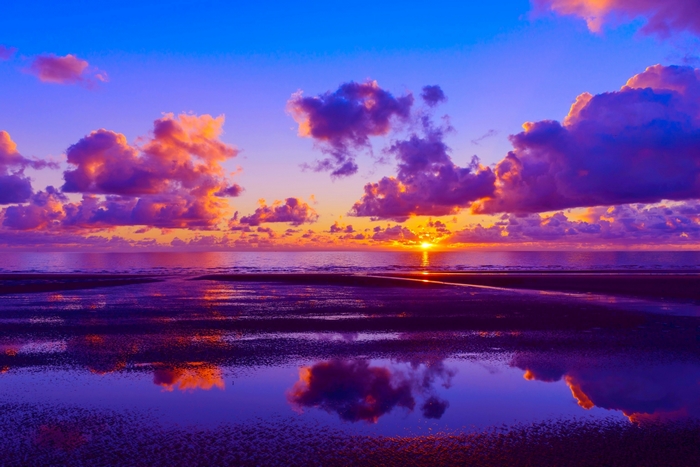 Sunset over the ocean with colorful clouds and reflections