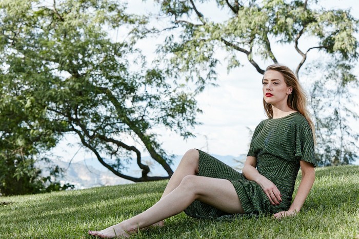 Amber Heard sitting on grass under a tree