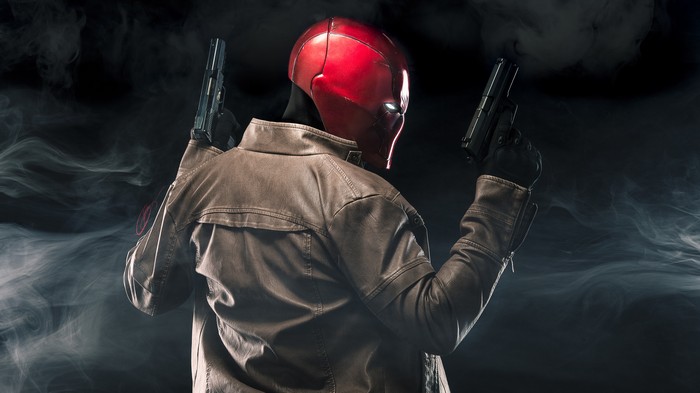 Red Hood holding two guns in smoke
