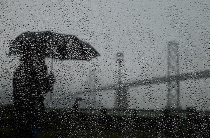 Person with umbrella in the rain with bridge