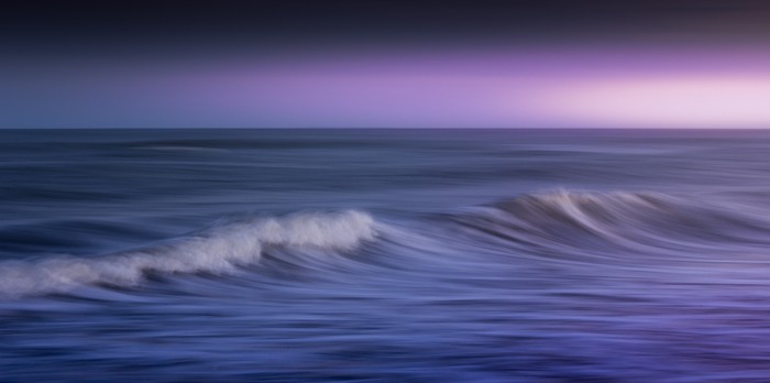 Ocean waves at dusk with purple sky