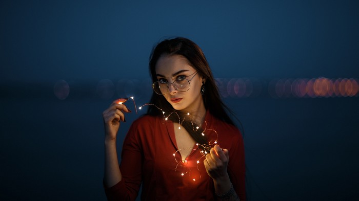 Woman with glasses holding fairy lights