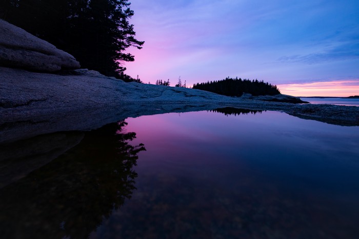 Sunset over rocky shore with water reflection 4K