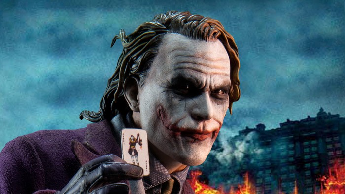 The Joker holding a playing card with a burning city background