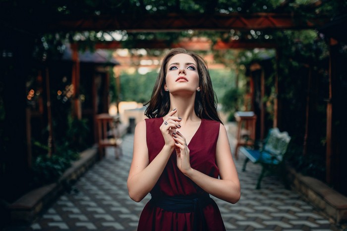 Brunette model in a burgundy dress looking up