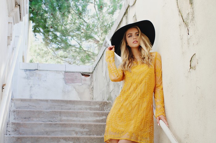 Marina Laswick wearing a yellow dress and black hat