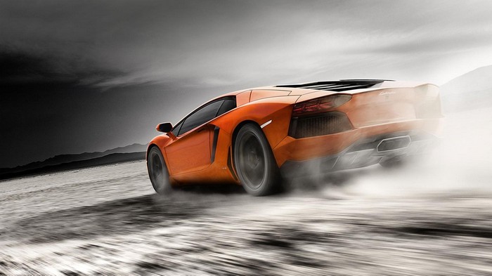 Orange Lamborghini Aventador drifting in dust