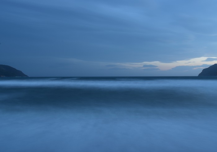 Ocean horizon at dusk with distant hills