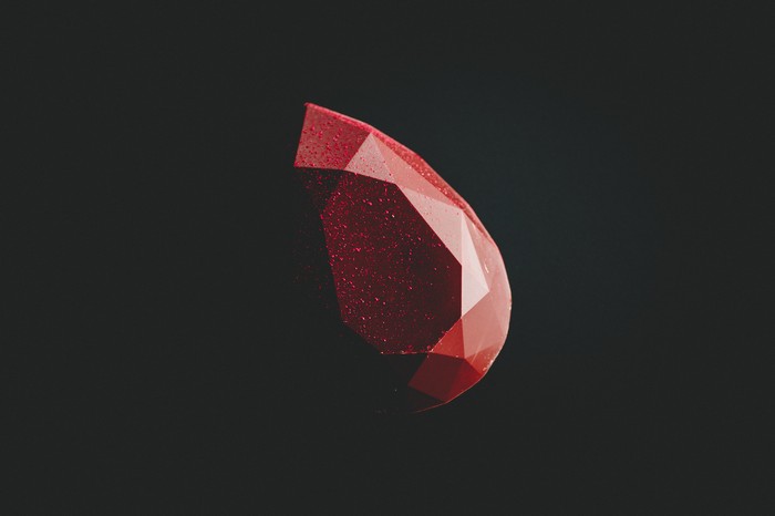 Red faceted gemstone on black background