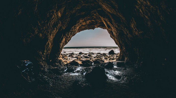 Cave entrance overlooking a rocky beach and ocean