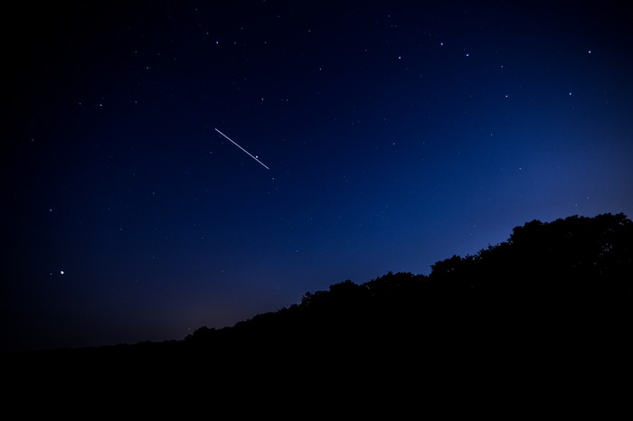 Shooting star in the night sky over a hill