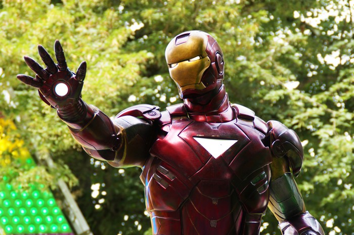 Iron Man with glowing hand in front of trees
