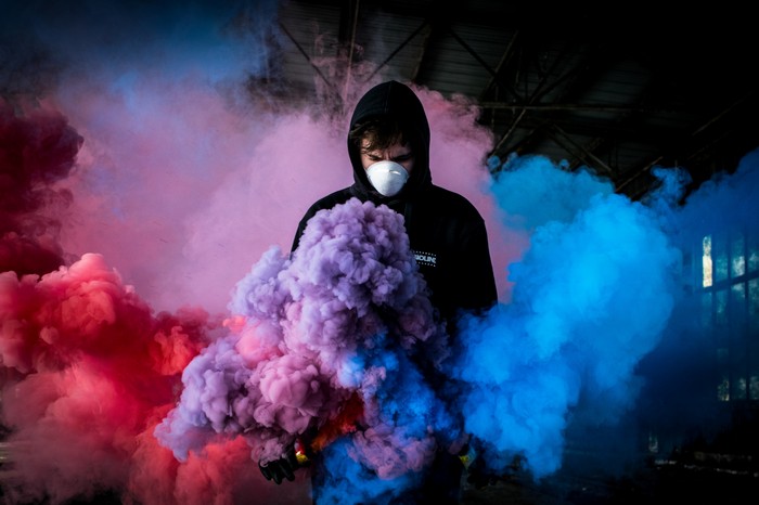 Person in hoodie with colorful smoke