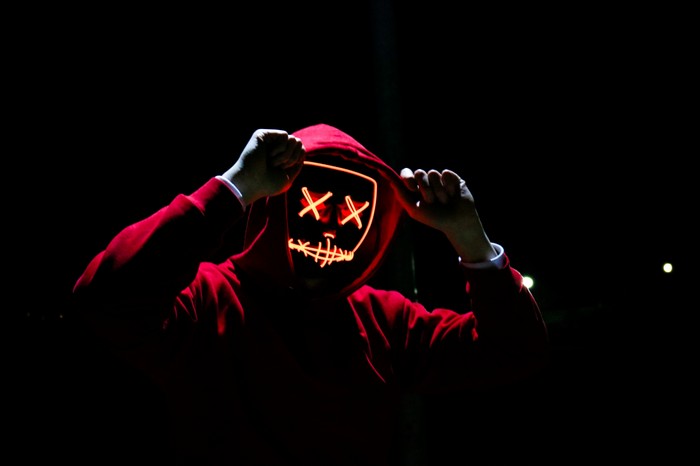 Person in red hoodie wearing a neon mask