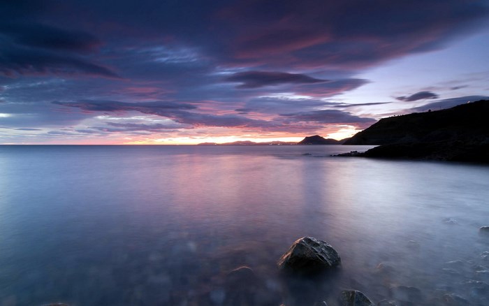 Sunset over the ocean with rocky shore