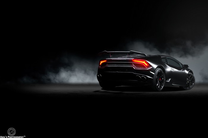 Black Lamborghini Huracan with red taillights in smoke