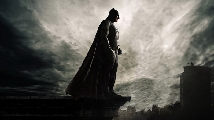 Batman standing on a rooftop overlooking a city