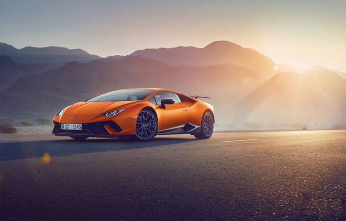 Orange Lamborghini Huracan on a desert road at sunset