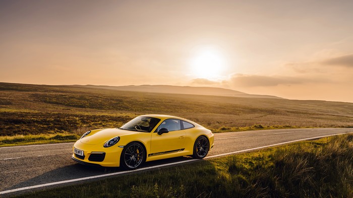 Yellow Porsche 911 on a road at sunset