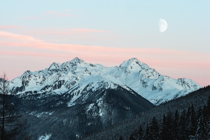 Snowy mountains with a half moon in the sky