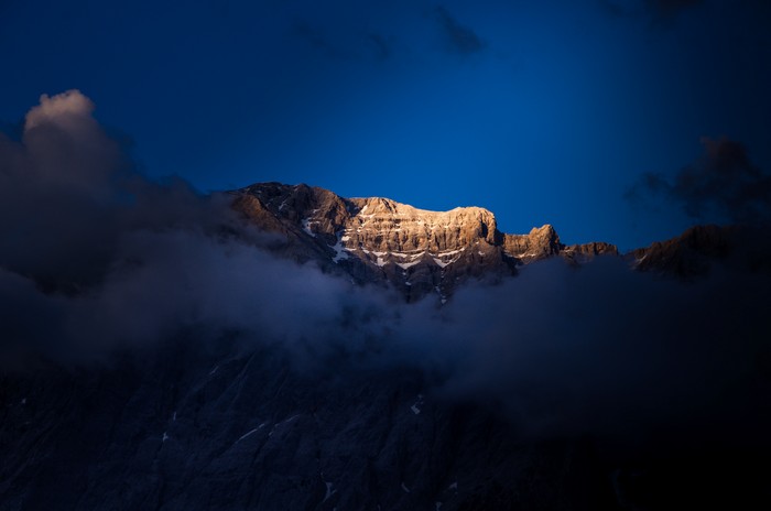 Sunlit mountain peak emerging from clouds