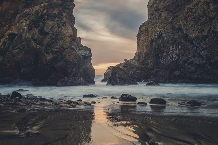 Waves crashing between rocky cliffs at dusk 4K